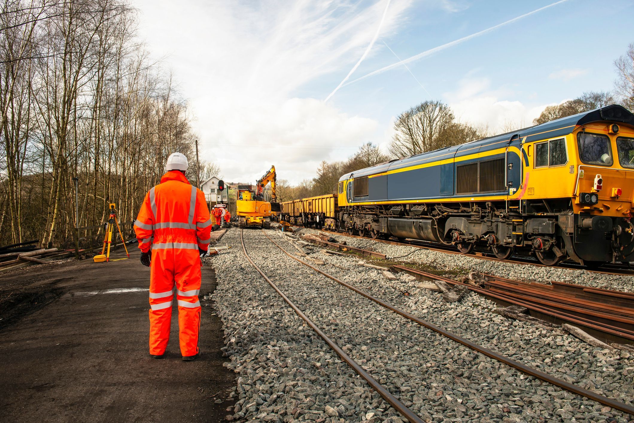 railway worker in orange safety gear stood by the railway line
