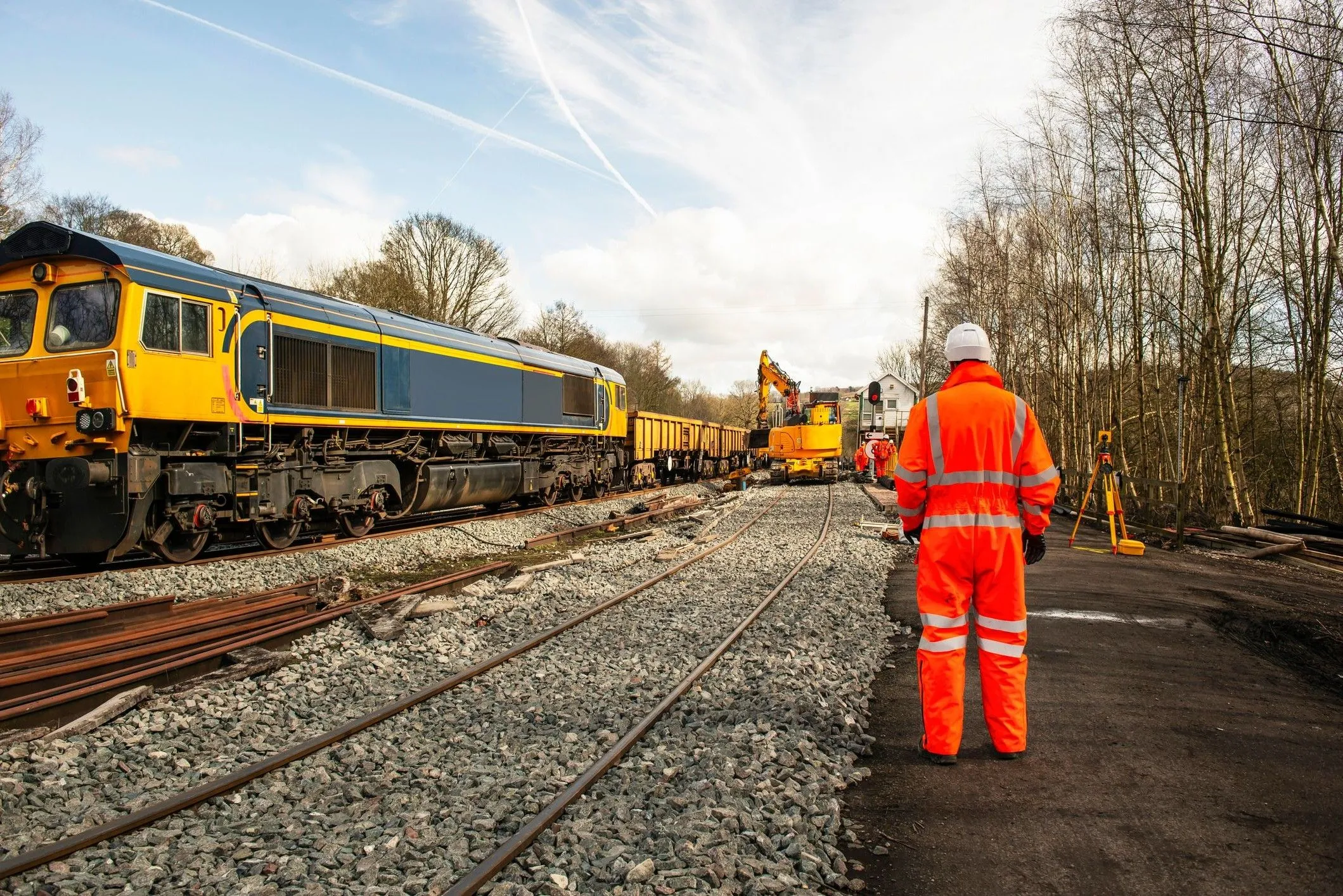 railway worker in orange safety gear stood by the railway reversed